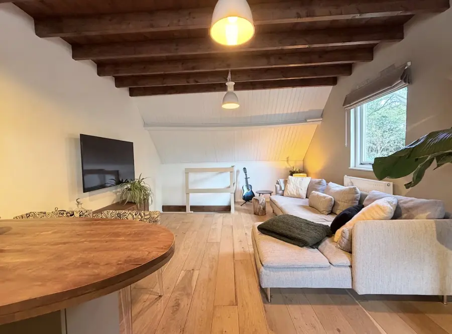 De zithoek van de BnB met een grote bank onder een houten balkenplafond